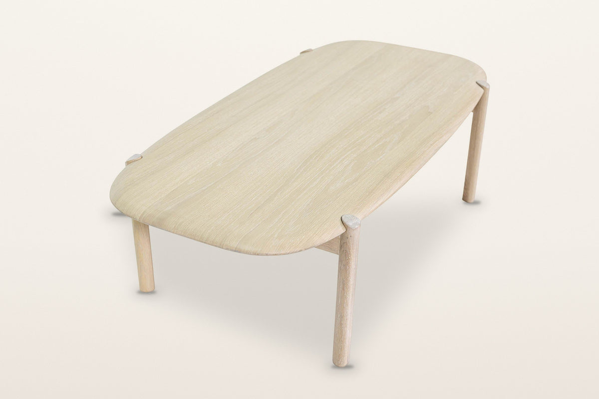 Rivello coffee table in Light Oak seen from above at the end on a warm white studio backdrop: the long top with its rounded c