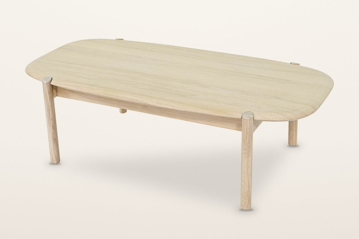 Rivello oak coffee table in Light Oak, three-quarter view from above on a warm white studio backdrop: a soft rectangular top