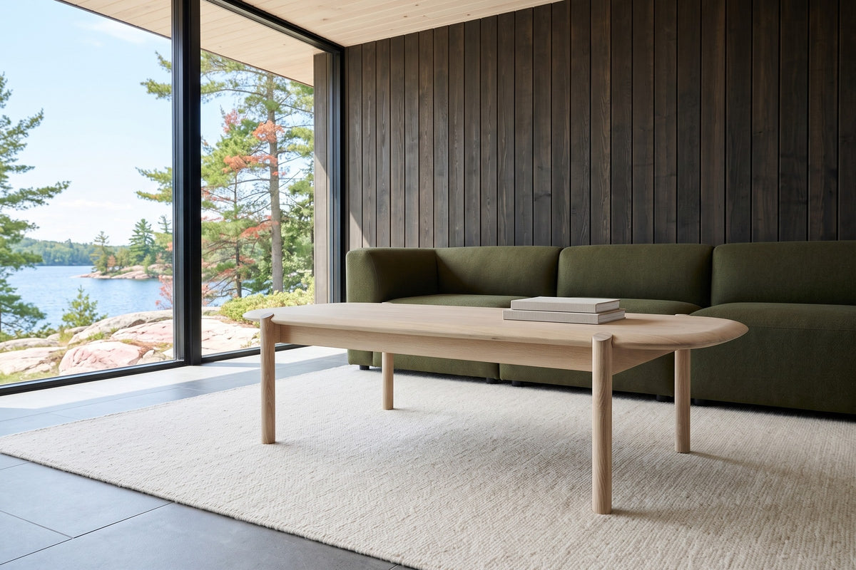 Rivello coffee table in Light Oak seen low from the corner in a Temagami island cottage, with dark cedar boards