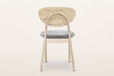 Rivello dining chair in Light Oak from behind on a warm white studio backdrop: the round rear legs bend into one oak arch beh