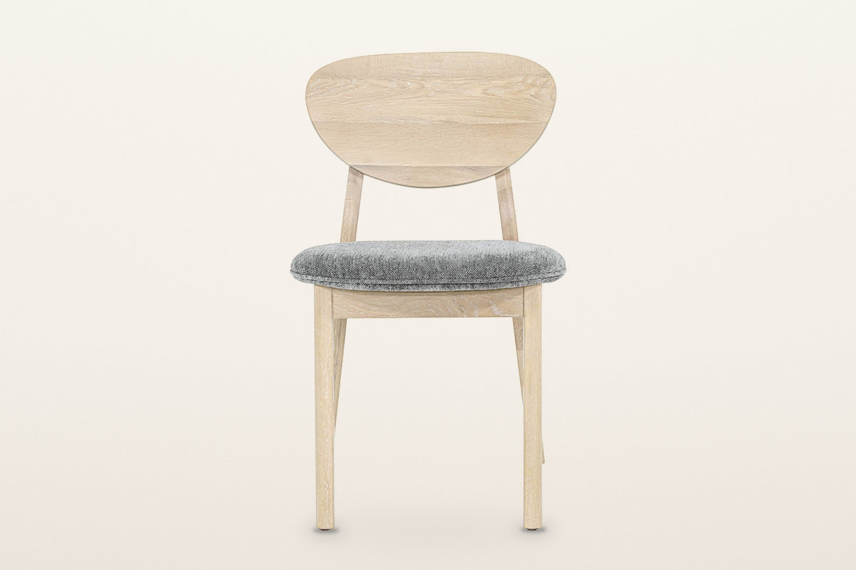 Rivello dining chair in Light Oak, straight front view on a warm white studio backdrop: the pebble back