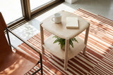 Rivello side table in Light Oak seen from above beside a cognac leather sling chair in a Lac-Beauport house