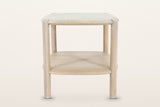 Rivello side table in Light Oak from the front, on a warm white studio backdrop: the top, the lower shelf and two round legs