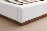 Close-up of the foot corner of the Roccascalegna bed: the white boucle rail on its recessed walnut plinth