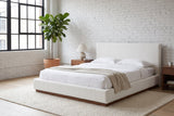 Roccascalegna boucle bed made up with white linen in a loft bedroom with a whitewashed brick wall