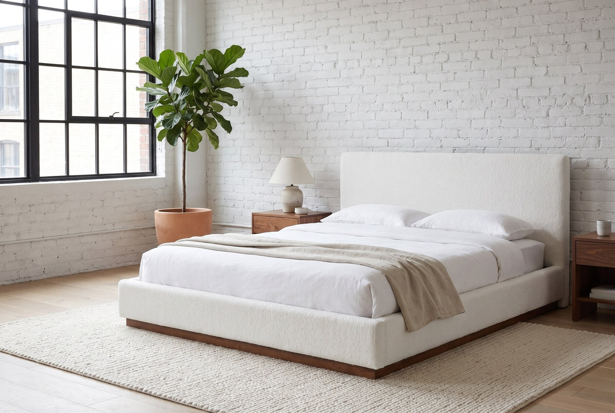 Roccascalegna boucle bed made up with white linen in a loft bedroom with a whitewashed brick wall
