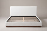 Roccascalegna boucle bed seen straight on from the foot: plain headboard, wood slats and a recessed walnut plinth