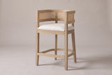 Sabaudia cane-back counter stool in Natural Ash, three-quarter view on a warm light-grey studio backdrop