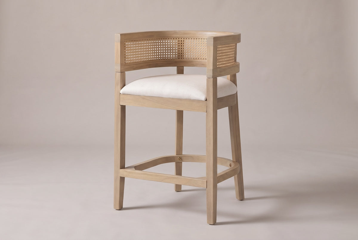 Sabaudia cane-back counter stool in Natural Ash, three-quarter view on a warm light-grey studio backdrop