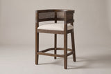 Sabaudia cane-back counter stool in Walnut, three-quarter view on a warm light-grey studio backdrop
