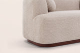 Close-up of the Almond boucle block arm and the walnut-brown rubberwood plinth with its rounded corner