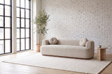 Sabbioneta sofa in Almond boucle against a white brick wall in a bright Montreal loft, an olive tree by the steel windows