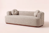 Sabbioneta Boucle Sofa in Almond boucle on a walnut-brown wooden plinth, three-quarter view on a warm off-white backdrop