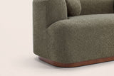 Close-up of the boucle block arm and the walnut-brown rubberwood plinth with its rounded corner