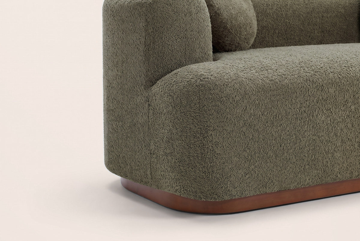 Close-up of the boucle block arm and the walnut-brown rubberwood plinth with its rounded corner