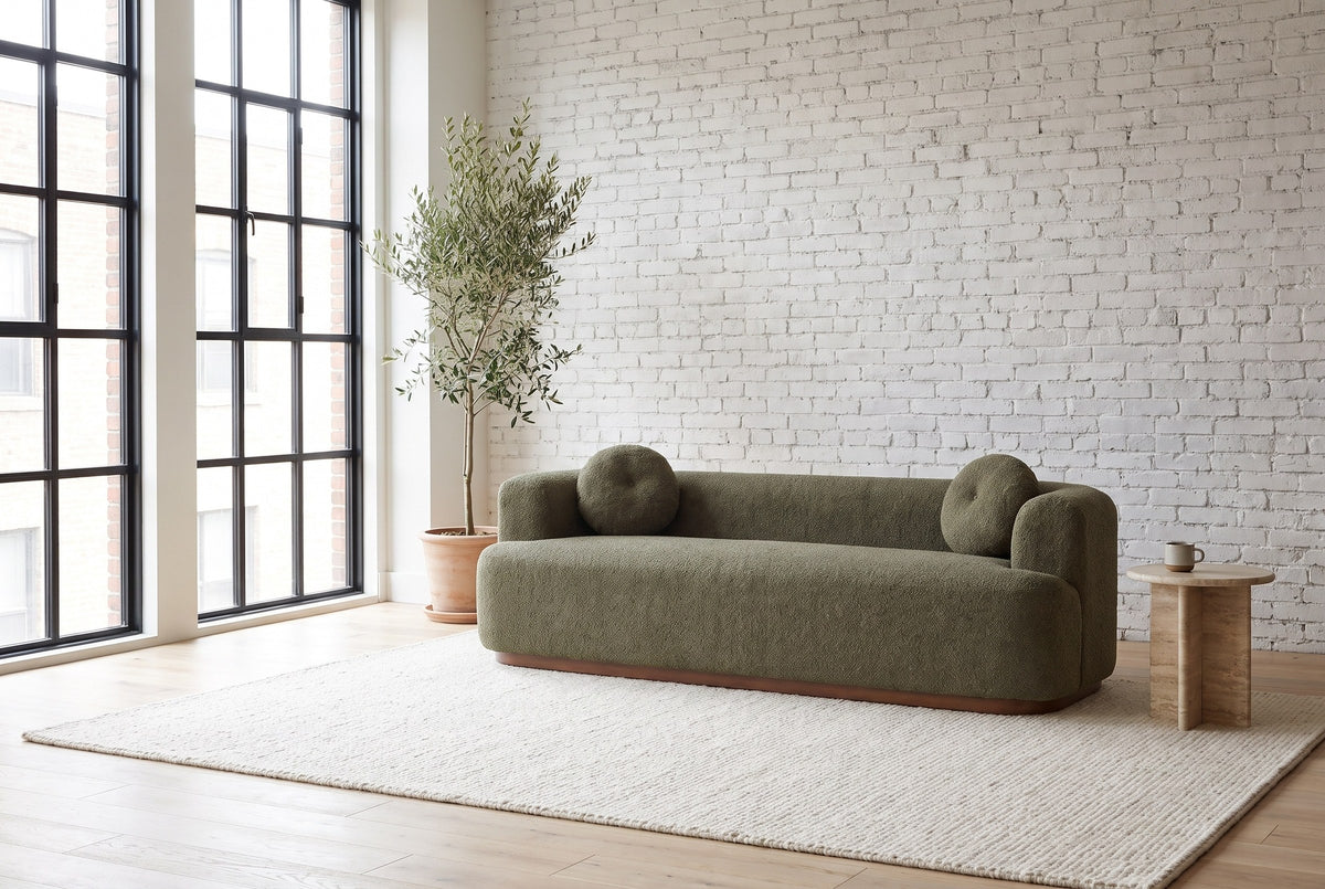 Sabbioneta sofa against a white brick wall in a bright Montreal loft, an olive tree by the steel windows