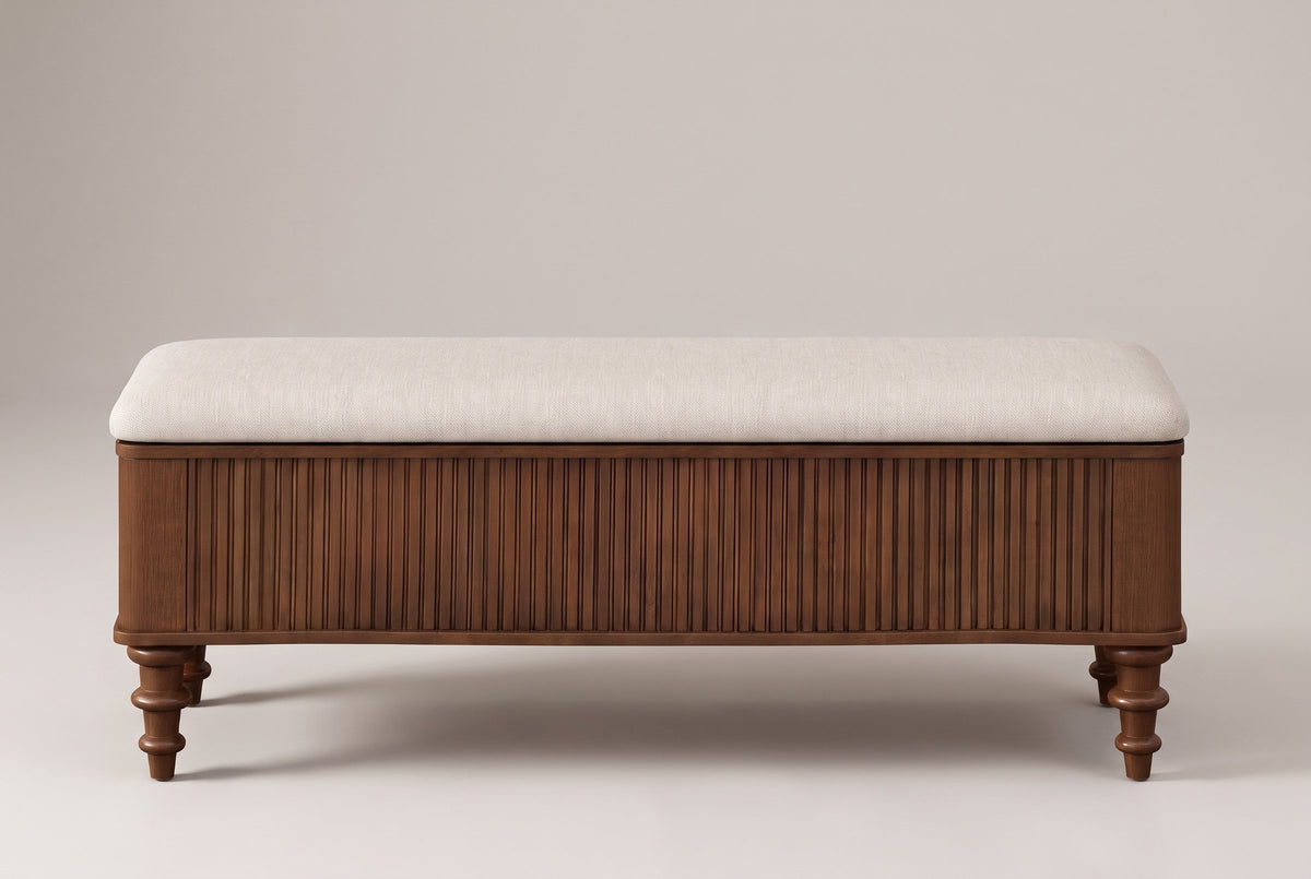 Salerno storage bench in walnut, straight front view: reeded front between rounded corners, a thin rim under the seat, four turned legs