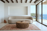 Sambuca coffee table in an Ericeira clifftop house, with white lime render, chestnut beams, a curved sand boucle sofa
