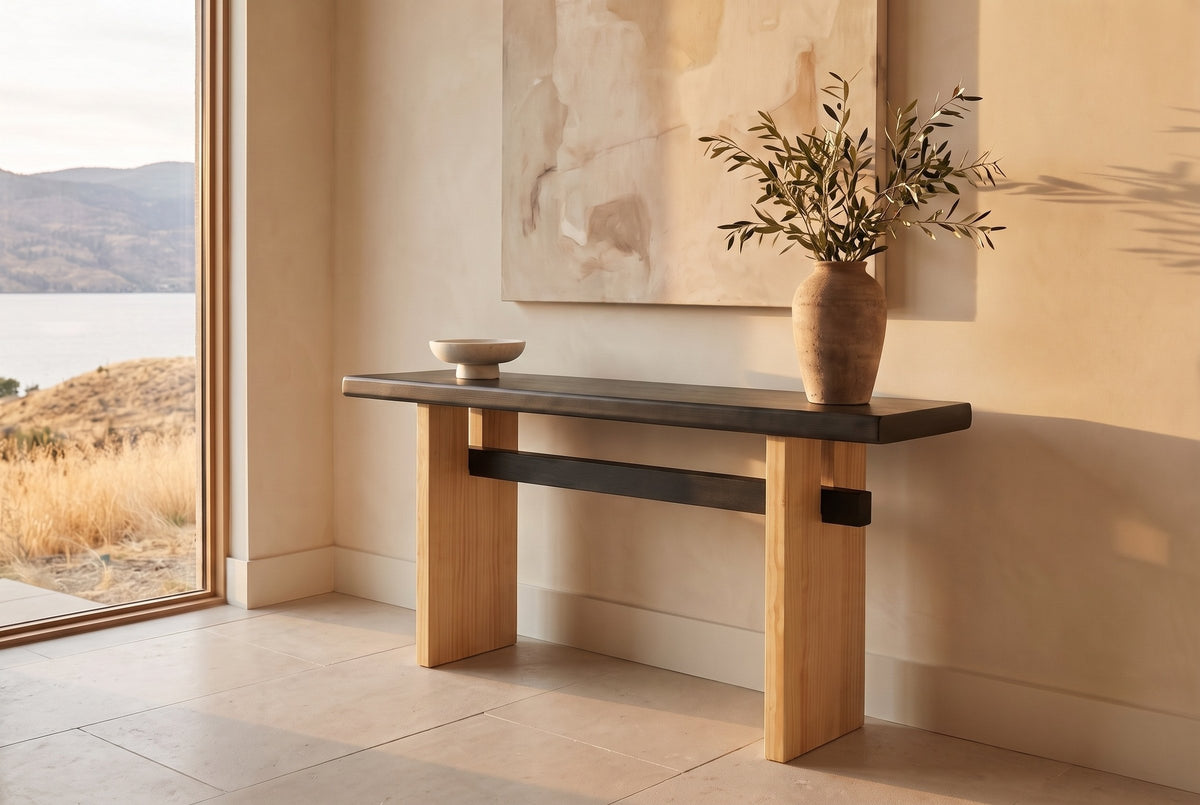 Sanremo console table with a black top and light wood legs in a limewashed lake-house entry in late sun