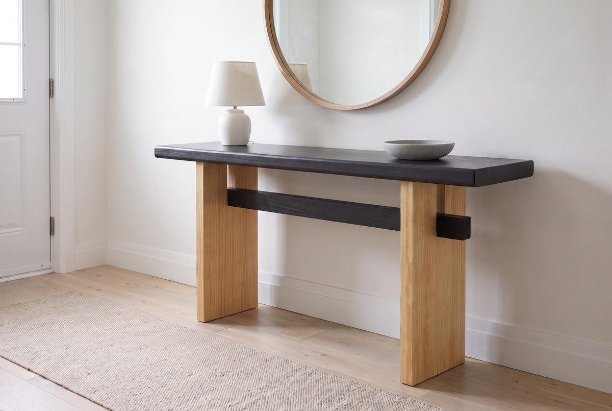 Sanremo console table with a black top and light wood legs in a white front hall under a round oak mirror