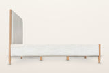Side view of the Sarnano bed on a warm white studio backdrop: the long upholstered rail