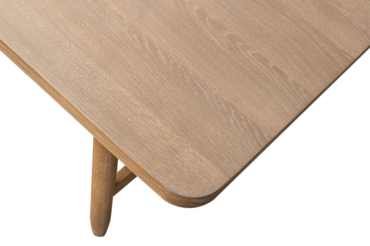 Close-up of a Sarnano corner in Sand: the softly rounded corner and edge of the oak top, a tapered leg below