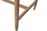 Close-up of a Sarnano leg in Sand: a round oak leg tapering to a soft foot, the low stretcher behind it