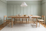 Sarnano dining table in Sand in a Montreal dining room with sage-green panelled walls and paper-cord chairs
