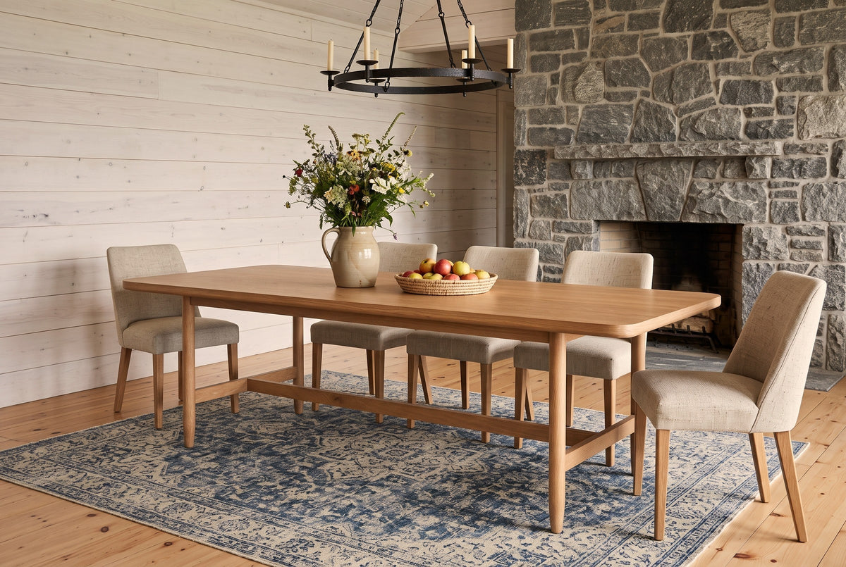 Sarnano dining table in Sand in a Muskoka cottage with whitewashed pine walls, a fieldstone fireplace