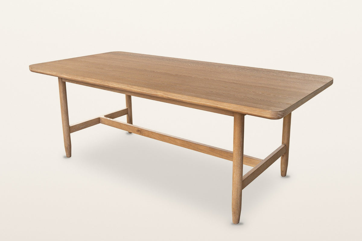 Sarnano mid-century oak dining table in Sand, three-quarter view on a warm white studio backdrop