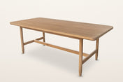 Sarnano mid-century oak dining table in Sand, three-quarter view on a warm white studio backdrop