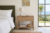 Front view of the Sarnano nightstand in Sand oak beside an olive upholstered bed in a bedroom in a Foz do Douro house, Porto