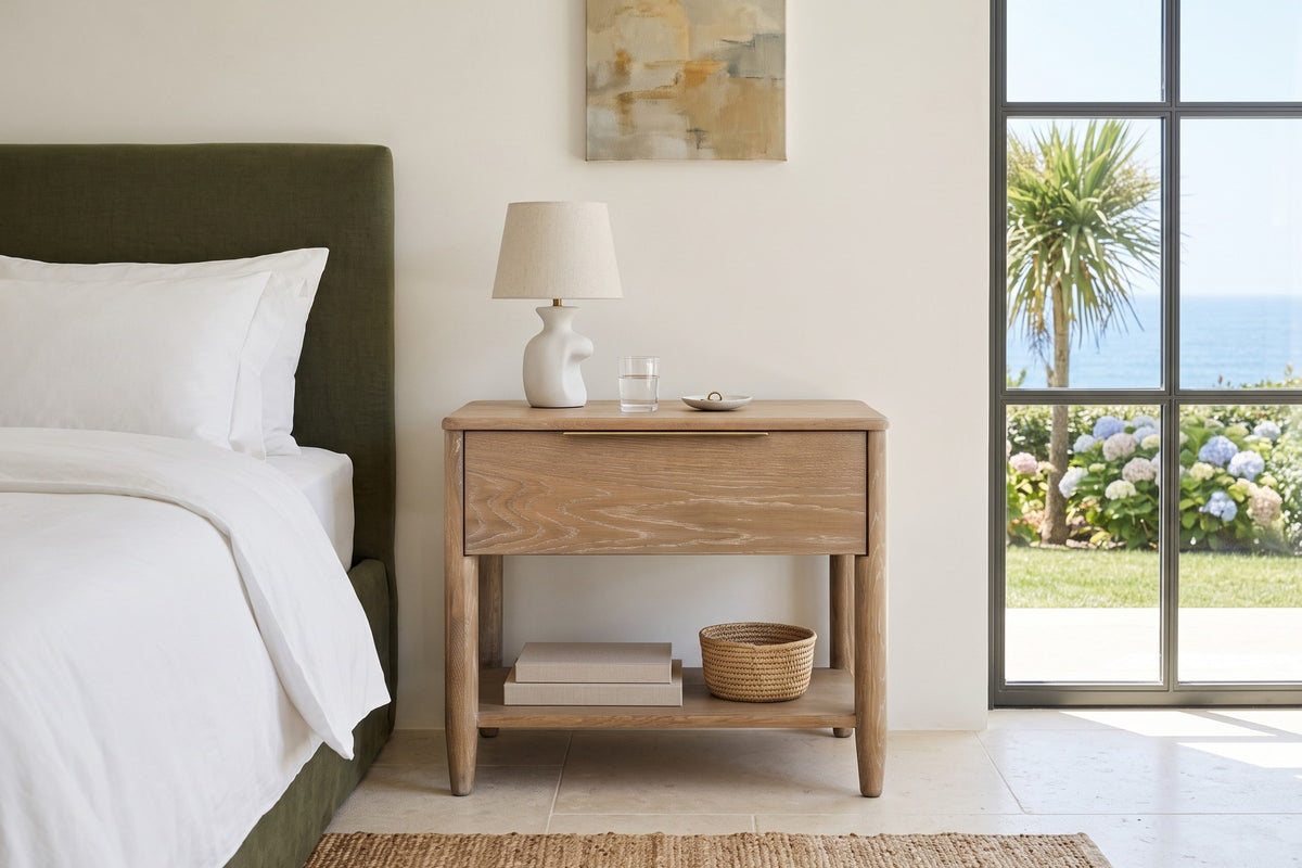 Front view of the Sarnano nightstand in Sand oak beside an olive upholstered bed in a bedroom in a Foz do Douro house, Porto