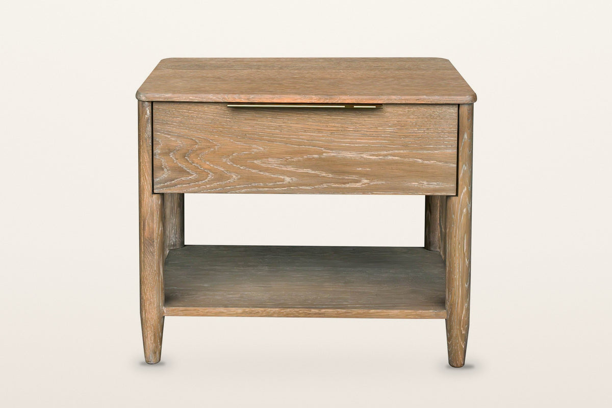 Sarnano nightstand in Sand, front view on a warm white studio backdrop: one wide drawer with a slim brass pull centred on its