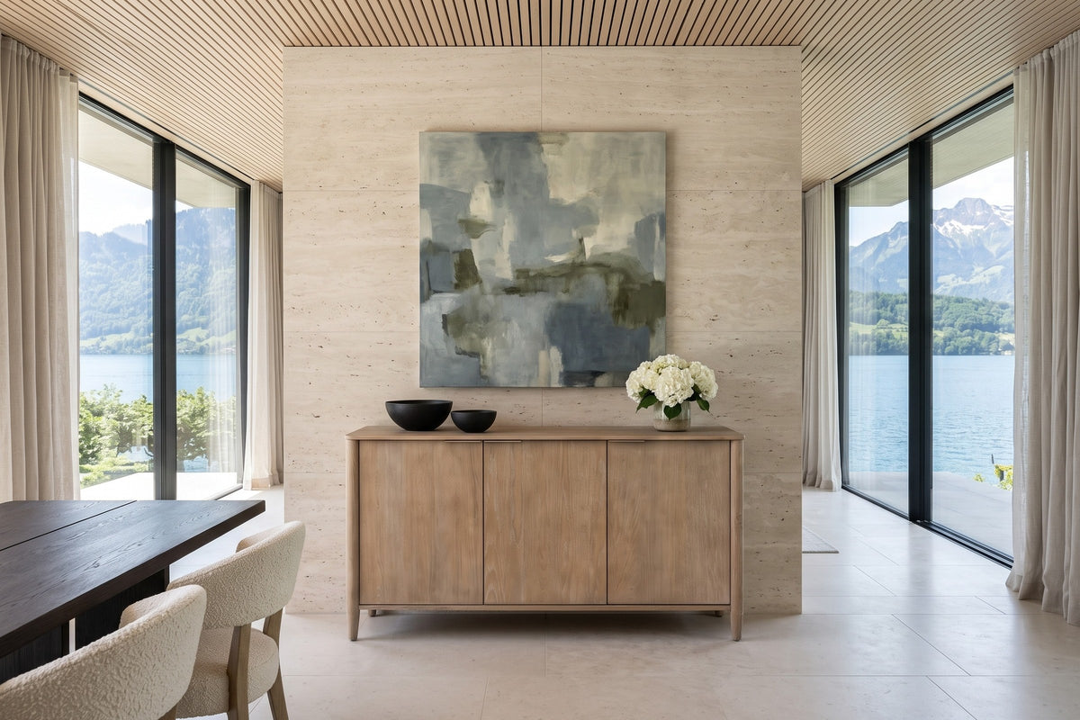 Sarnano sideboard in Sand, front view, against a double-height travertine wall with abstract art in a Vitznau lakeside villa