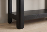 Close-up of a rounded black solid pine leg running past the thick lower shelf into a short rounded foot