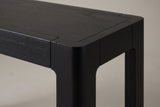 Close-up of a top corner: the framed wood veneer top, the rounded leg top and the curved corner where the leg meets the apron