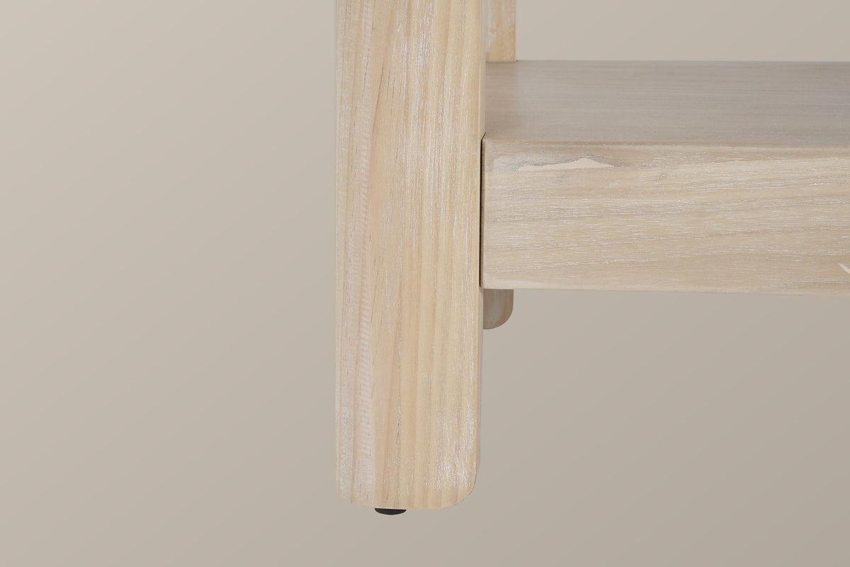 Close-up of a rounded solid pine leg in the natural finish running past the thick lower shelf into a short rounded foot