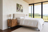 Sarteano nightstand in Pecan mango beside a linen bed in a Beamsville bedroom, with warm white plaster walls