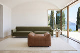 Sassocorvaro ottoman in Antique Sienna facing the camera before an olive velvet sofa in a Sorrento cliff villa