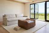 Sassocorvaro ottoman in Antique Sienna seen from a raised corner in a Vineland farmhouse, before an oatmeal sofa