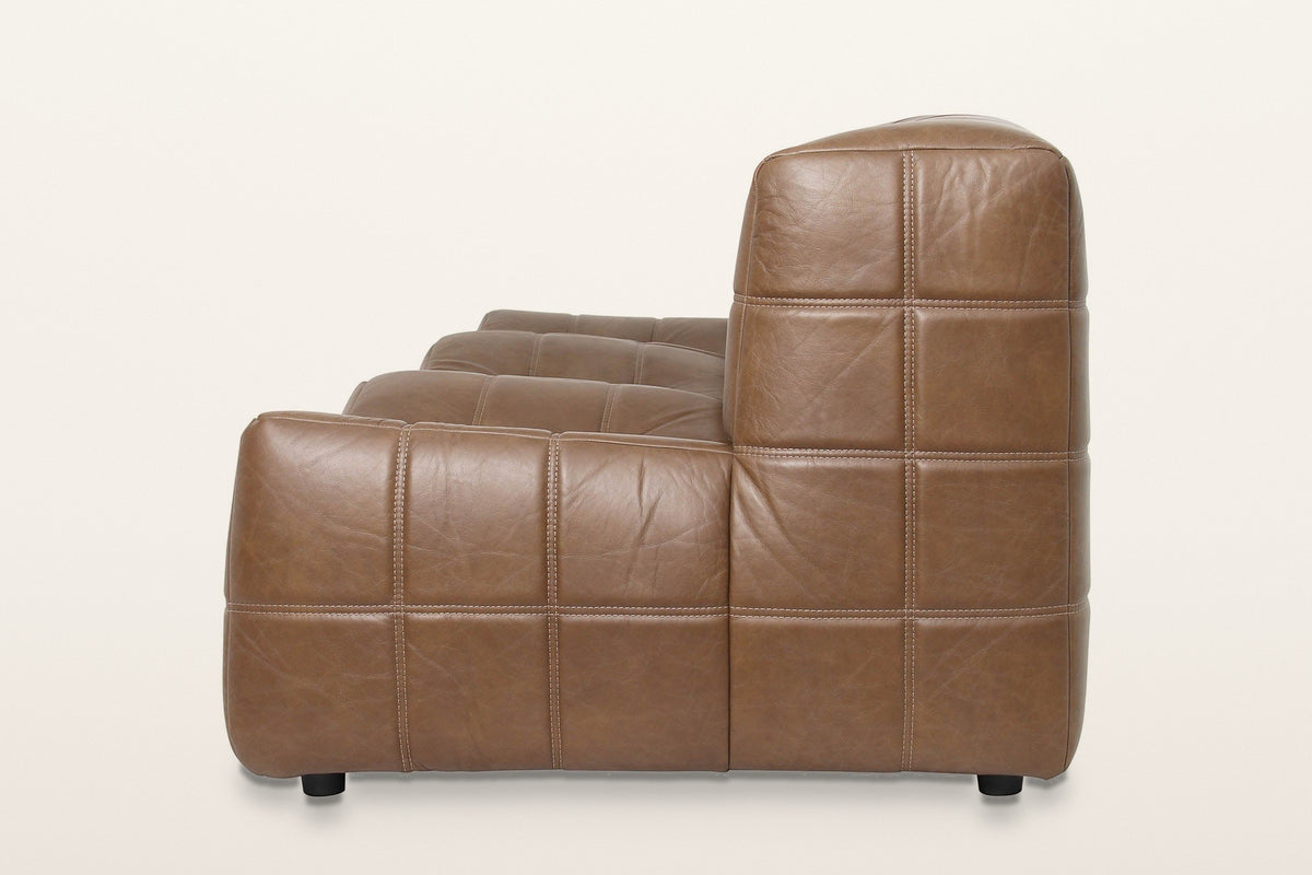 Sassocorvaro sofa in Antique Sienna from the end on a warm white studio backdrop: the low seat block in front of the taller b