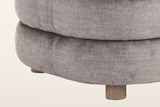 Close-up of the stacked rolls of the Sauze chair in dark taupe velvet and one short round foot