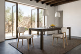 Two Savoca dining chairs in Porcelain Chenille at a long dark elm table in a Tavira courtyard house, with white plaster