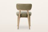 The back of the Savoca dining chair in Sage Green leather on a warm white studio backdrop