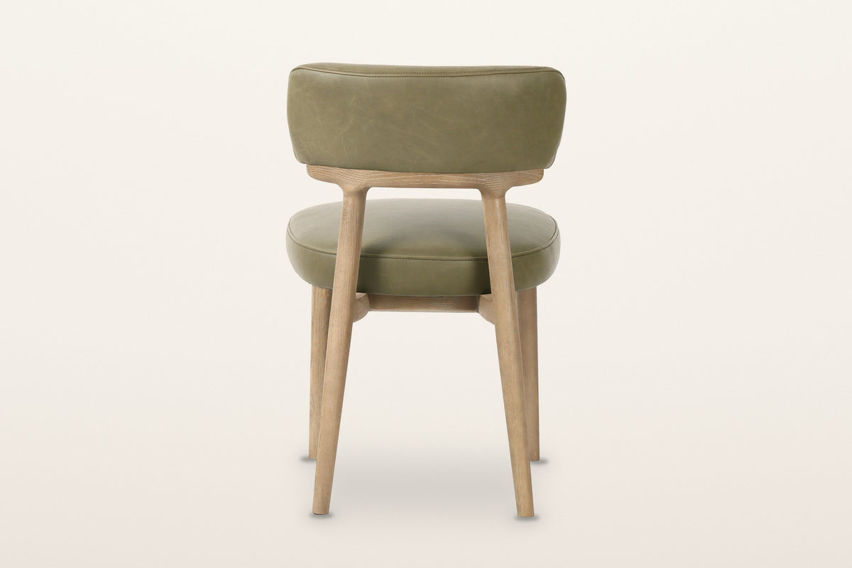 The back of the Savoca dining chair in Sage Green leather on a warm white studio backdrop