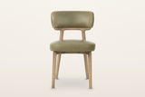 Savoca dining chair in Sage Green leather, front view on a warm white studio backdrop