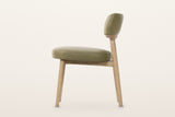 Savoca dining chair in Sage Green leather, side view on a warm white studio backdrop