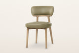 Savoca dining chair in Sage Green leather, three-quarter view on a warm white studio backdrop
