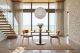 Two Savoca dining chairs in Tawny leather at a round walnut pedestal table in a Goderich house above Lake Huron